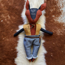 Charger l'image dans la galerie, Handmade linen coyote spirit guardian doll in black and cedar tones, featuring tribal-inspired embroidered details on its forehead, dressed in a mustard vest, leather belt and necktie, and rolled-up jeans.